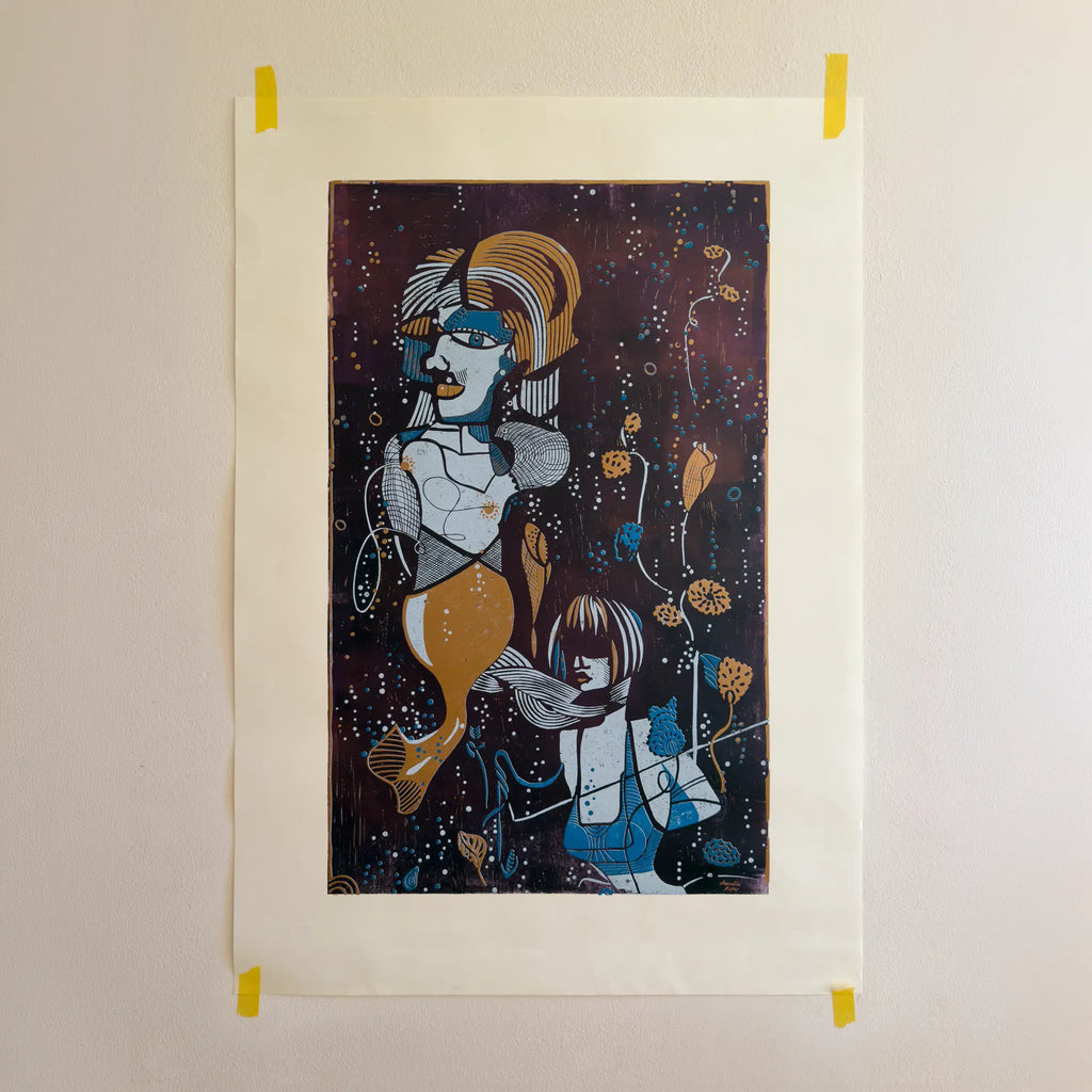 The linocut “Underwater Love” in copper and blue, attached to a beige wall with yellow tape.