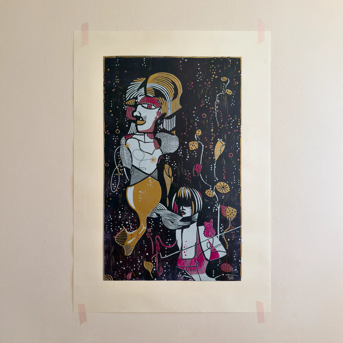 The linocut “Underwater Love” in gold and purple, attached to a beige wall with pink tape.
