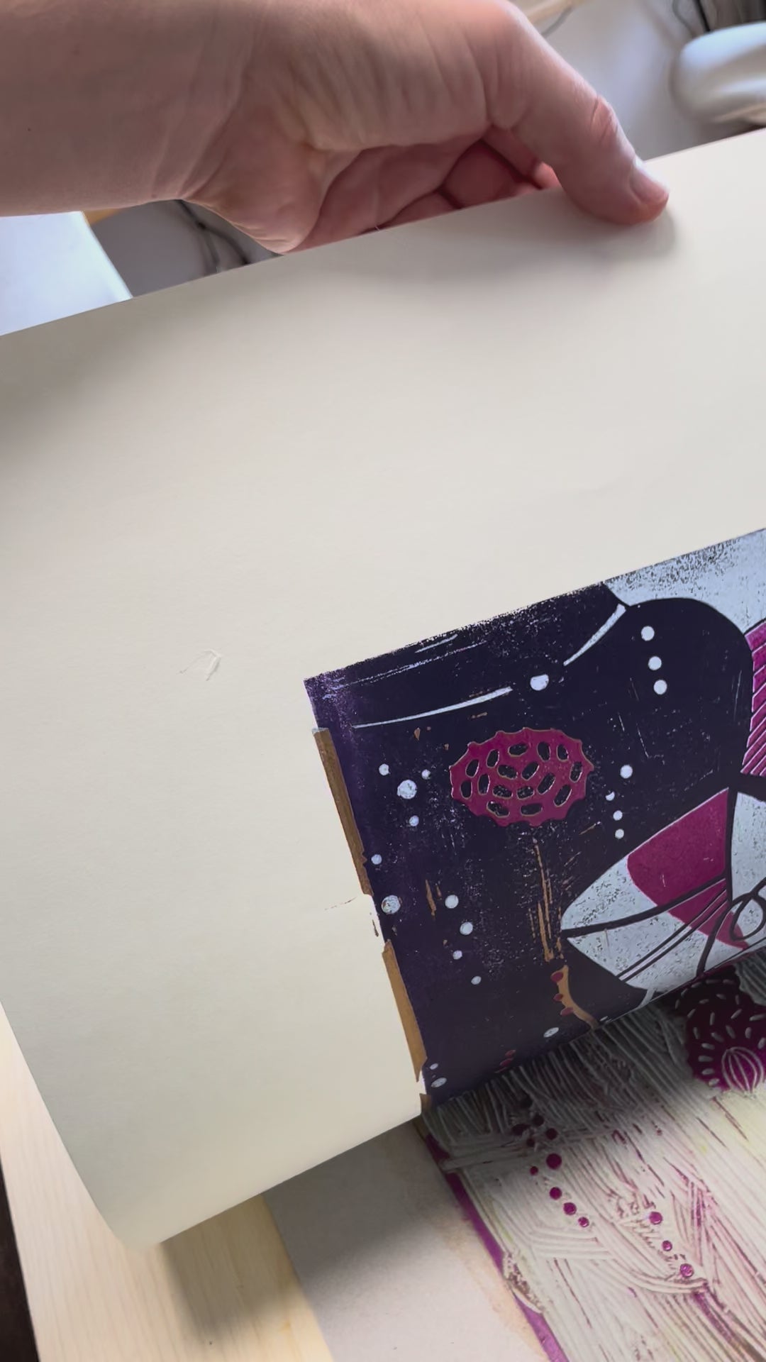 Paper is peeled off the linoleum printing block and shows close-ups of the linoleum print “Underwater Love gold/purple.”